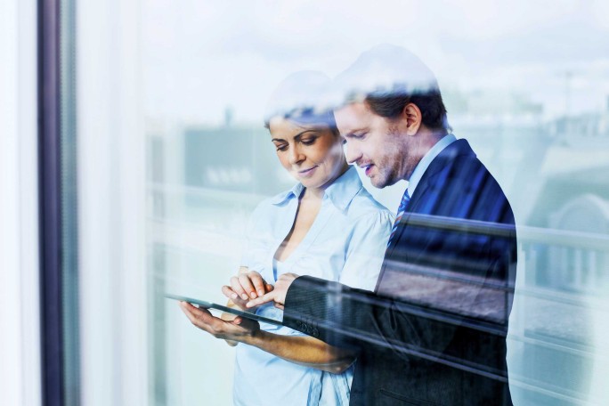 2 Kolleg:innen besprechen Unterlagen auf einem Tablet