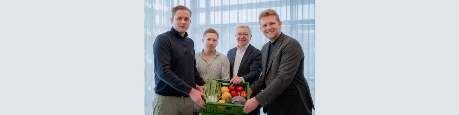 Vier Personen halten eine Box mit Bio-Obst und -Gemüse