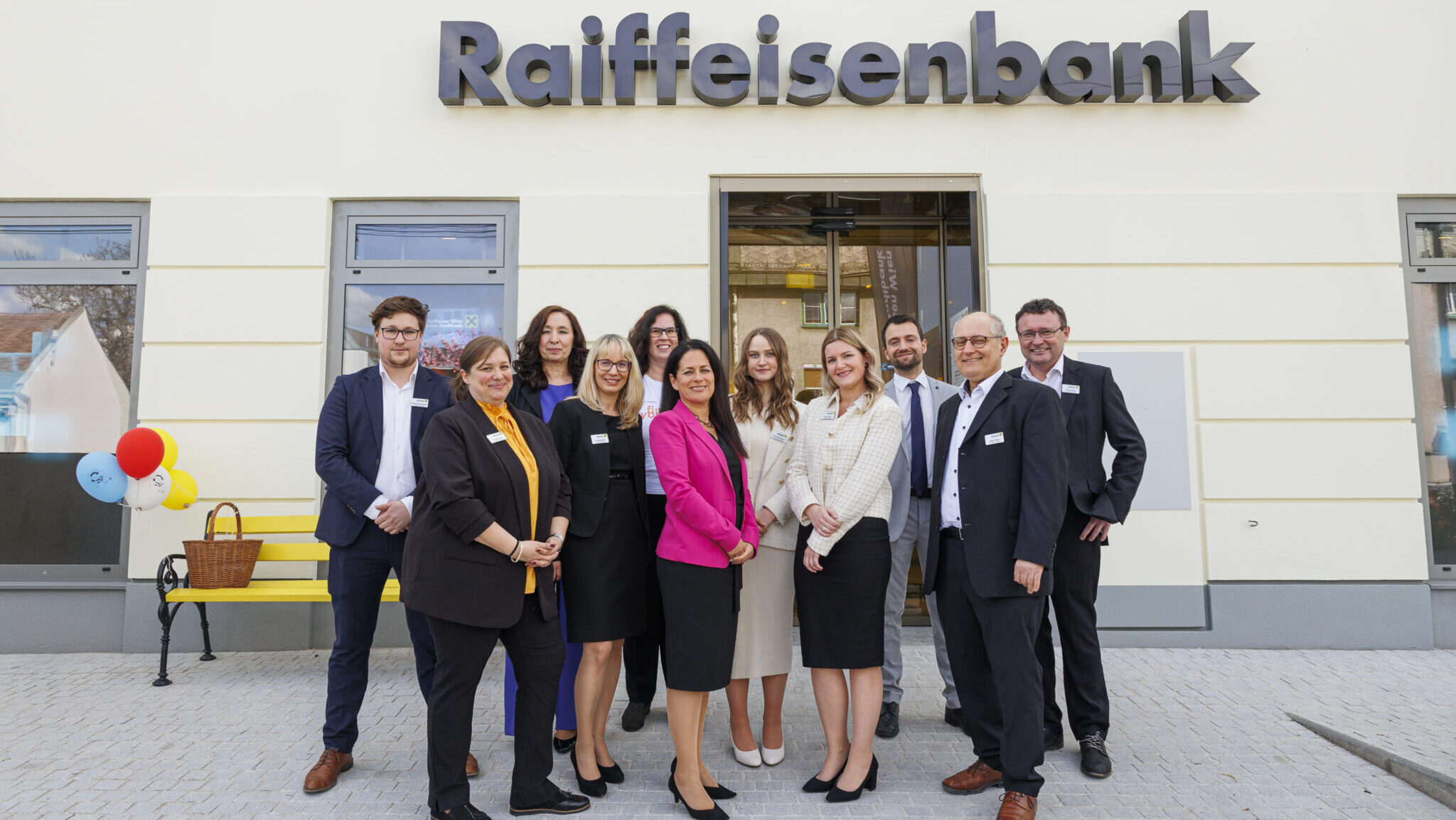 Eine Gruppe posiert vor der neuen Stadtbank-Filiale für eine Foto