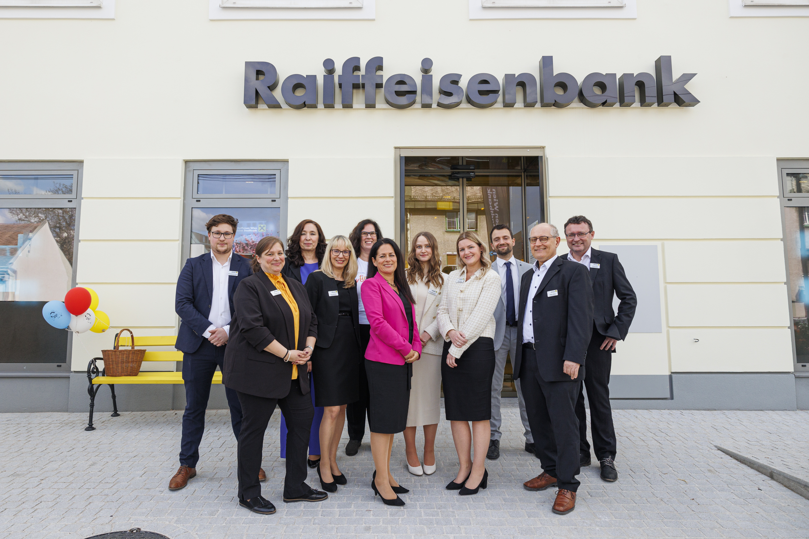 Eine Gruppe posiert vor der neuen Stadtbank-Filiale für eine Foto